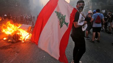 Un manifestant arbore le drapeau libanais pendant un affrontement entre les protestataires et les forces de l'ordre, près du Parlement libanais à Beyrouth, lors de la mobilisation du mercredi 4 août 2021, un an après l'explosion.