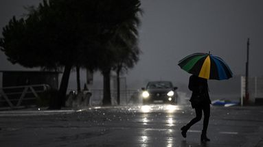 Une femme tenant un parapluie traverse une rue sous la pluie avant la tempête Ciaran, le 1er novembre 2023, à Arcachon, dans le sud-ouest de la France. 