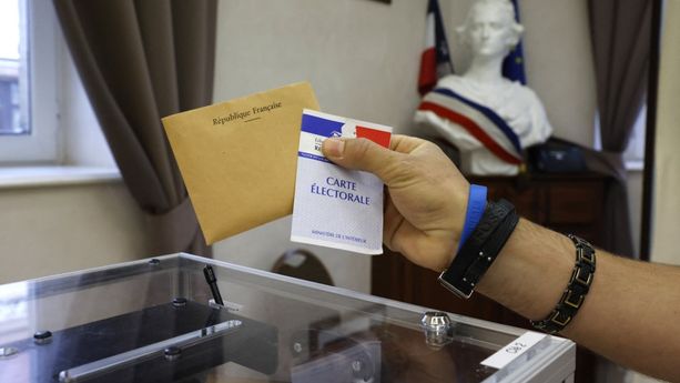 Un électeur détient une carte électorale et un bulletin de vote avant de voter dans un bureau de vote à Etaples, dans le nord de la France.